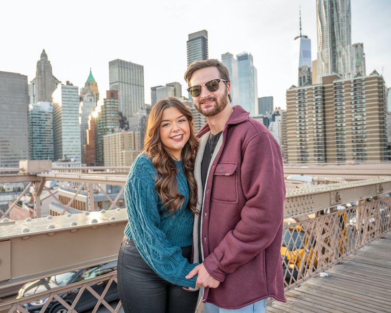 couple posing on the Brooklyn Bridge for a photo