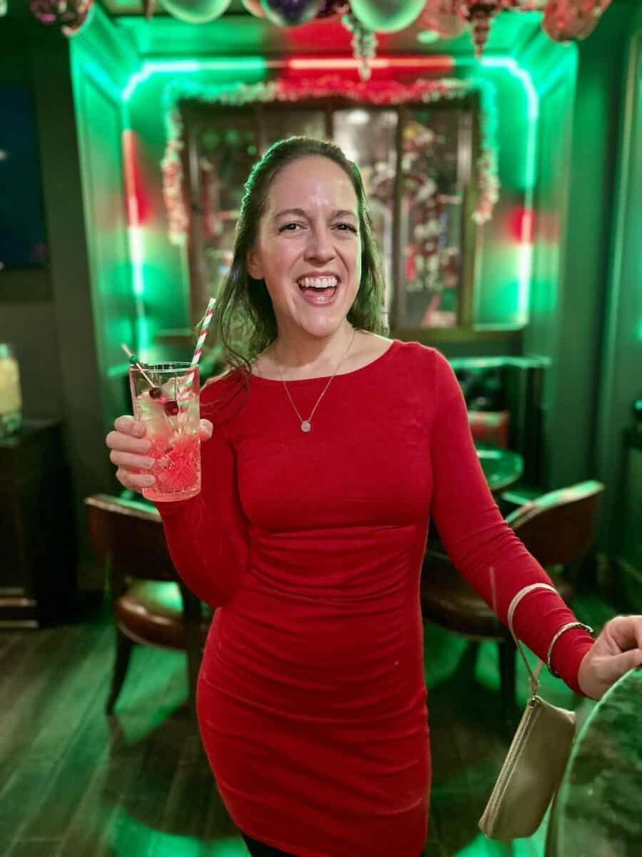woman in a red dress holding a cocktail at Blitzen's Christmas Bar in NYC