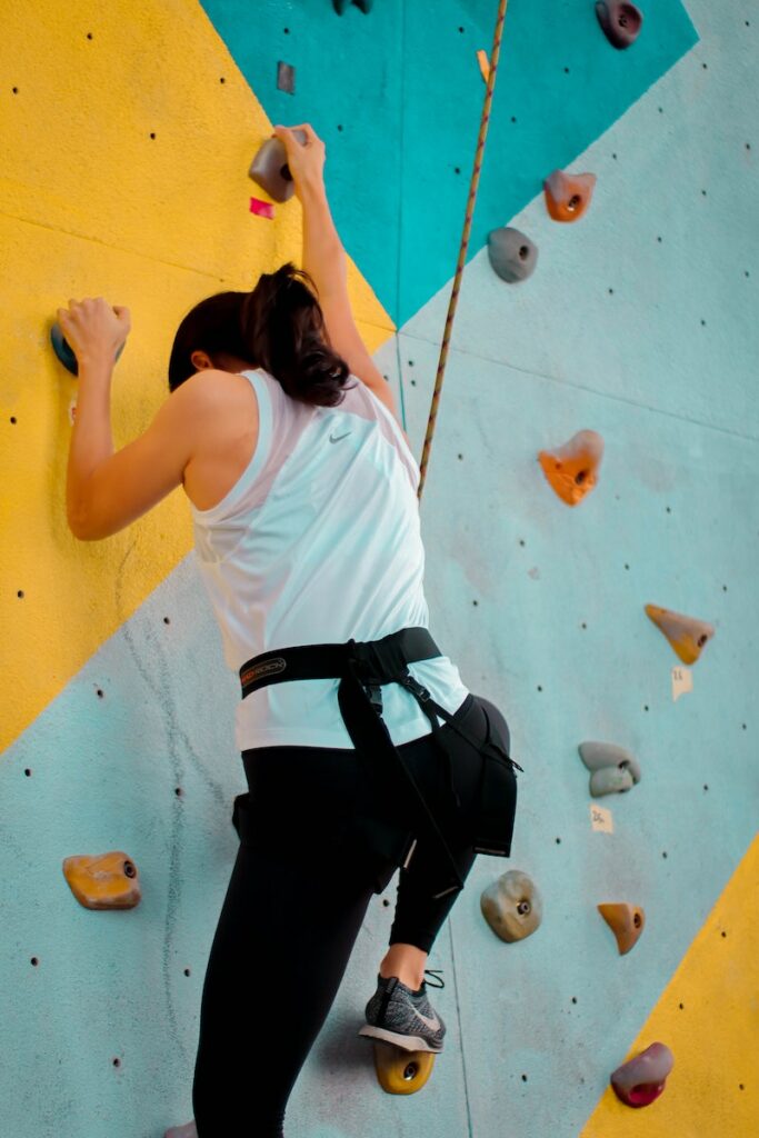 woman climbing up a rock wall