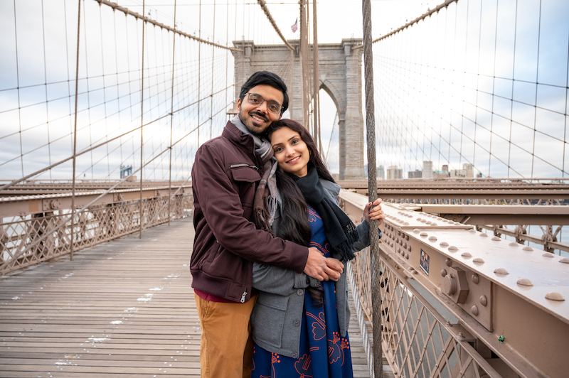 couple posing for NYC engagement photos on the Brooklyn Bridge